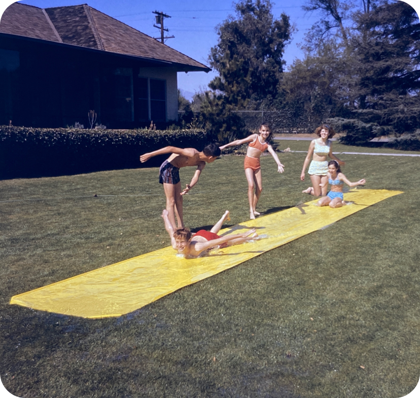 Children playing on a Slip 'N Slide on Spud's front lawn.